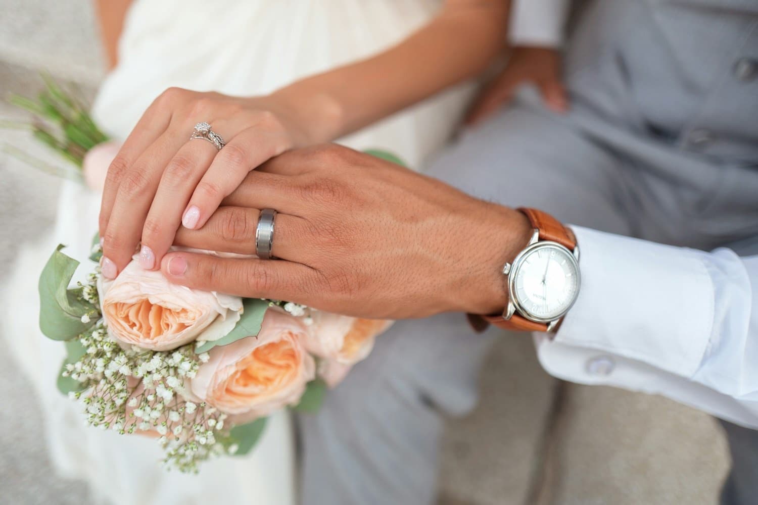 A couple's hands resting together, one wearing a wedding ring